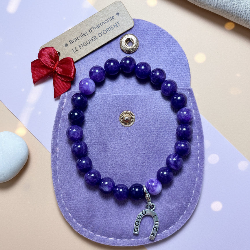 Bracelet d’harmonie en perles naturelles d’améthyste violette, orné d’un bijou symbolique et présenté dans une trousse en velours, création Le Figuier d’Orient.