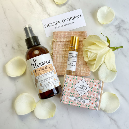 Coffret cadeau naturel et élégant Le Figuier d’Orient comprenant une eau florale de fleur d’oranger HERBÉOS, un parfum roll-on fleur d’oranger, un savon artisanal Jardin Amazigh et une pochette en tissu naturel, présenté dans une ambiance douce, lumineuse et raffinée, idéale pour un rituel visage et bien-être apaisant.