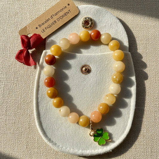 Bracelet d’harmonie en perles naturelles d’agate jaune, orné d’un bijou porte-bonheur et présenté dans une trousse en velours beige, création Le Figuier d’Orient.