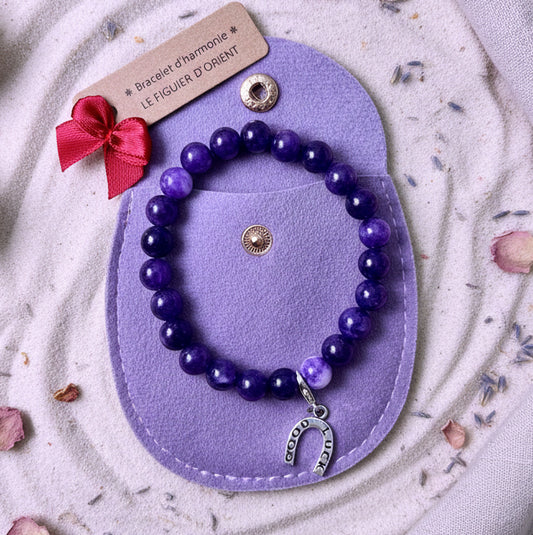 Bracelet d’harmonie en perles naturelles d’améthyste violette, orné d’un bijou symbolique et présenté dans une trousse en velours, création Le Figuier d’Orient.