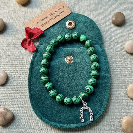 Bracelet d’harmonie en perles naturelles de malachite verte, orné d’un petit bijou symbolique et présenté dans une trousse en velours avec étiquette Le Figuier d’Orient.