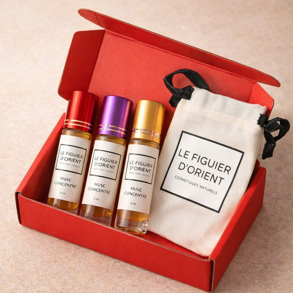 Coffret rouge Le Figuier d’Orient contenant trois muscs concentrés 8 ml (bouchons rouge, violet et doré) accompagnés de la pochette signature en coton – parfums de niche suisses en format découverte.